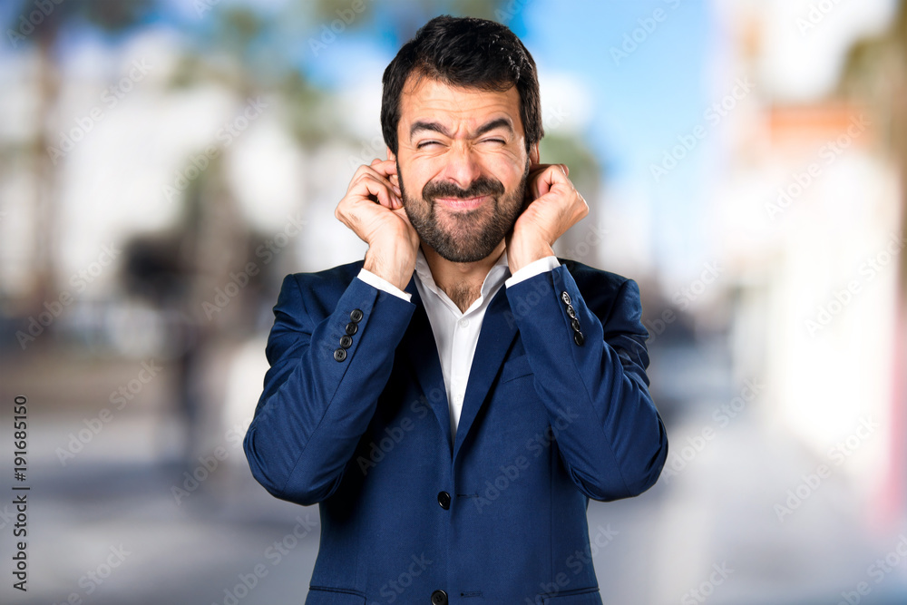 Handsome man covering his ears on unfocused background Handsome man covering his ears on unfocused background