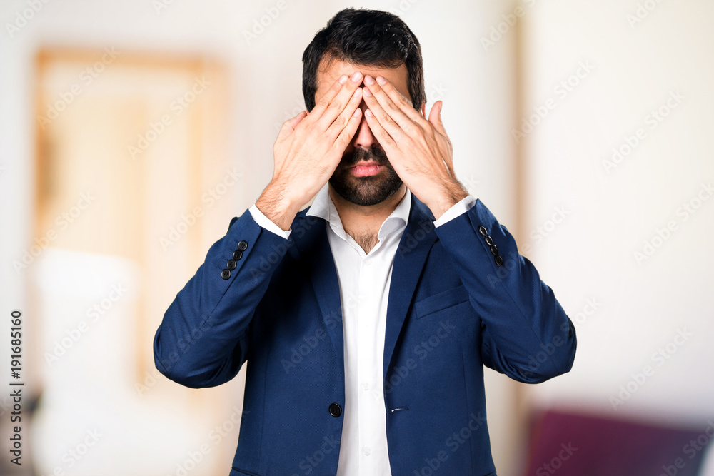Handsome man covering his eyes on unfocused background Handsome man covering his eyes on unfocused background