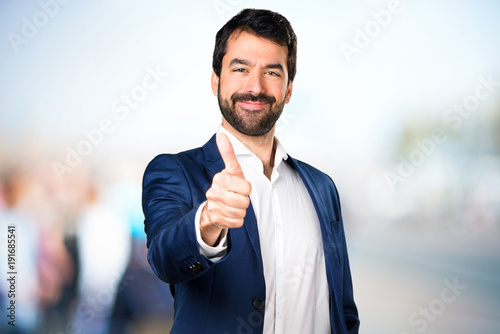 Handsome man with thumb up on unfocused background