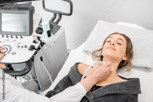 Young woman patient during the ultrasound examination of a thyroid lying on the couch in medical office photo