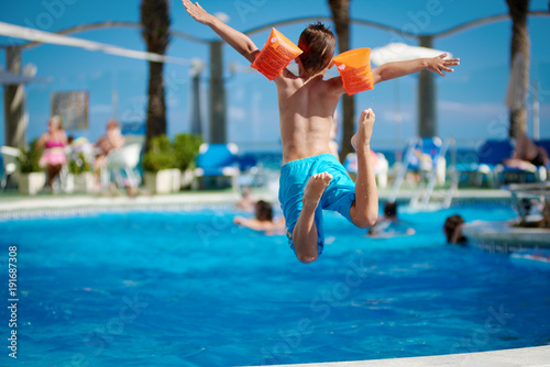 Caucasian boy jumping into the pool.