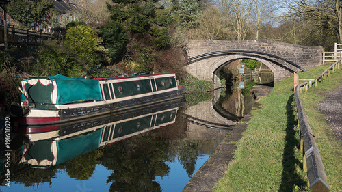 Foto A peaceful scenic view of a narrowboat with reflections moored on a canal with a