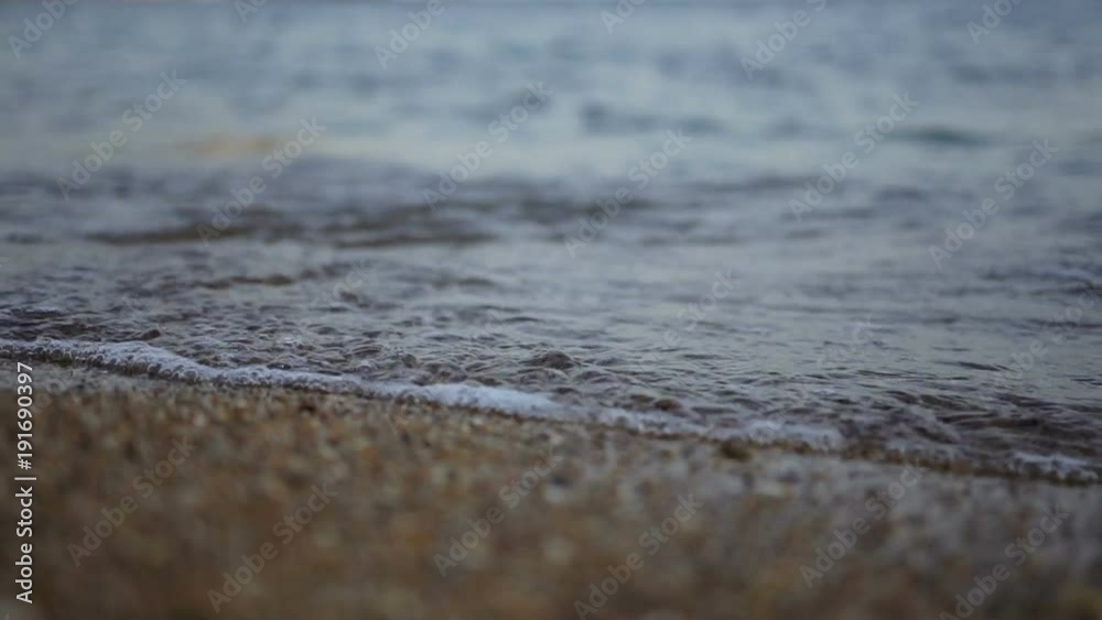 Close up of the light sea waves rolling on the beach. Sea coast of small stones. Outdoor