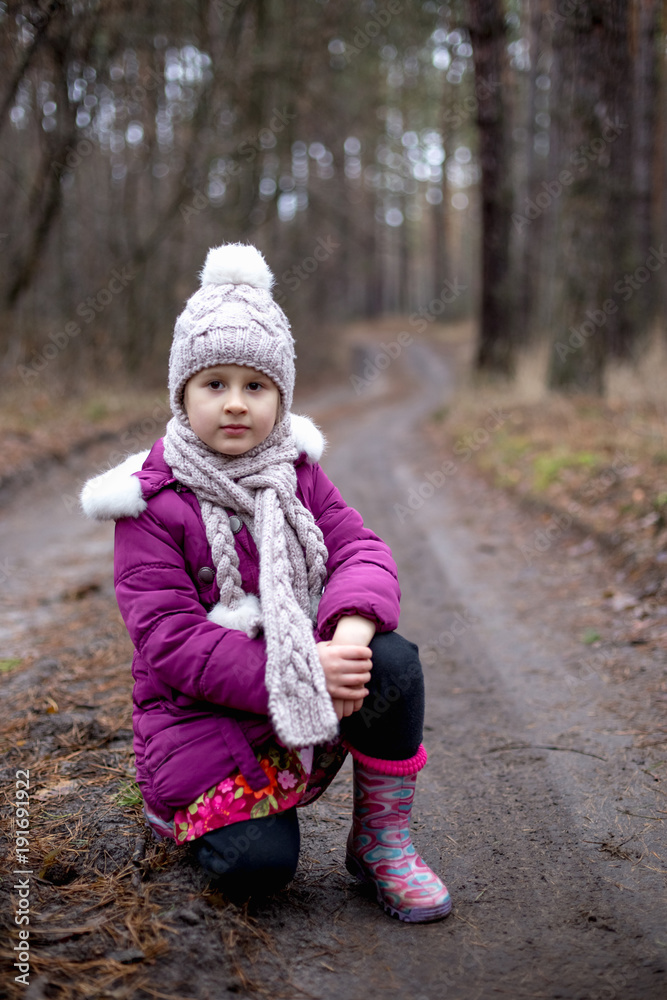 Little cute girl posing on the road in the pine forest in autumn time Little cute girl posing on the road in the pine forest in autumn time