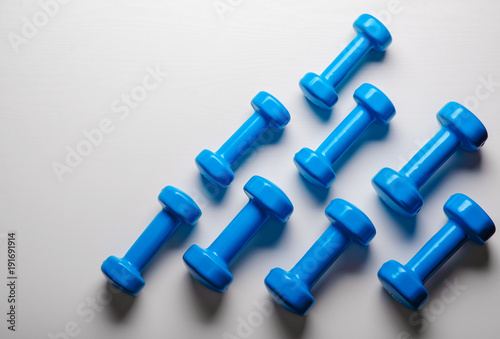 many blue dumbbells on a white background ,concept preparing to fitness sports equipment top view mock up