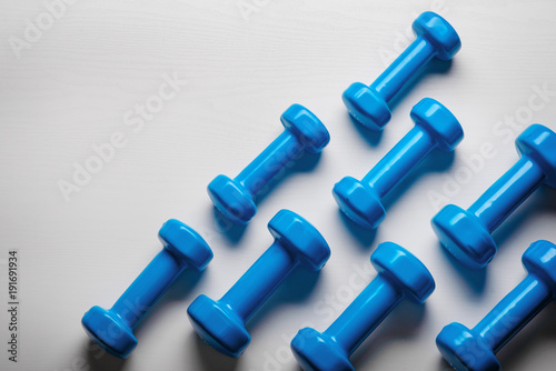 many blue dumbbells on a white background ,concept preparing to fitness sports equipment top view mock up © cezarksv