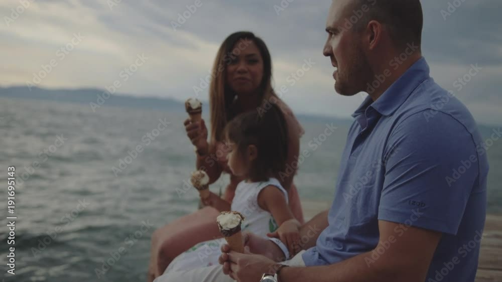 Mixed Race authentic family sitting on a dock eating ice cream