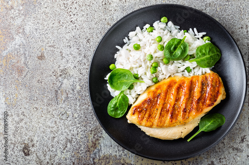 Chicken breast or fillet, poultry meat grilled and boiled white rice with green peas and fresh spinach leaves. Healthy diet menu for lunch