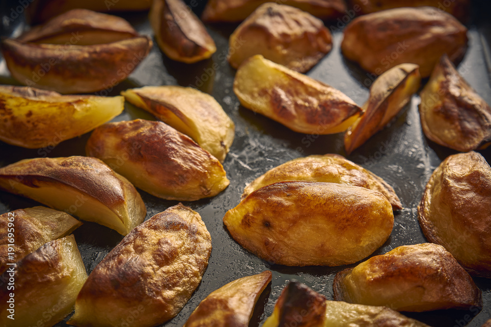 Golden baked potato wedges on a baking tray Golden baked potato wedges on a baking tray