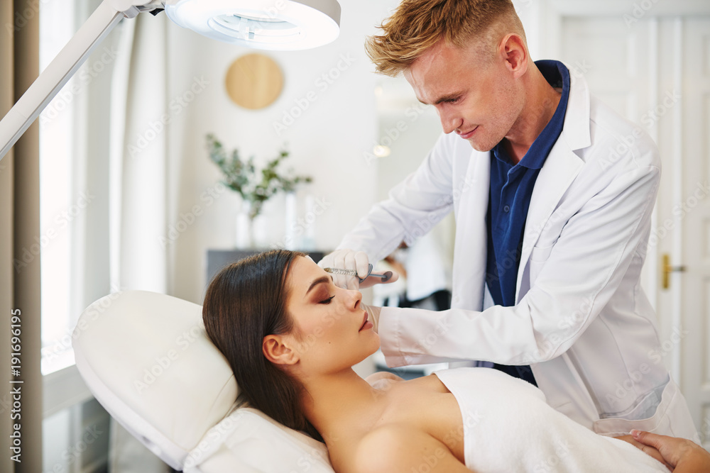 Doctor performing a botox injection on an attractive female client