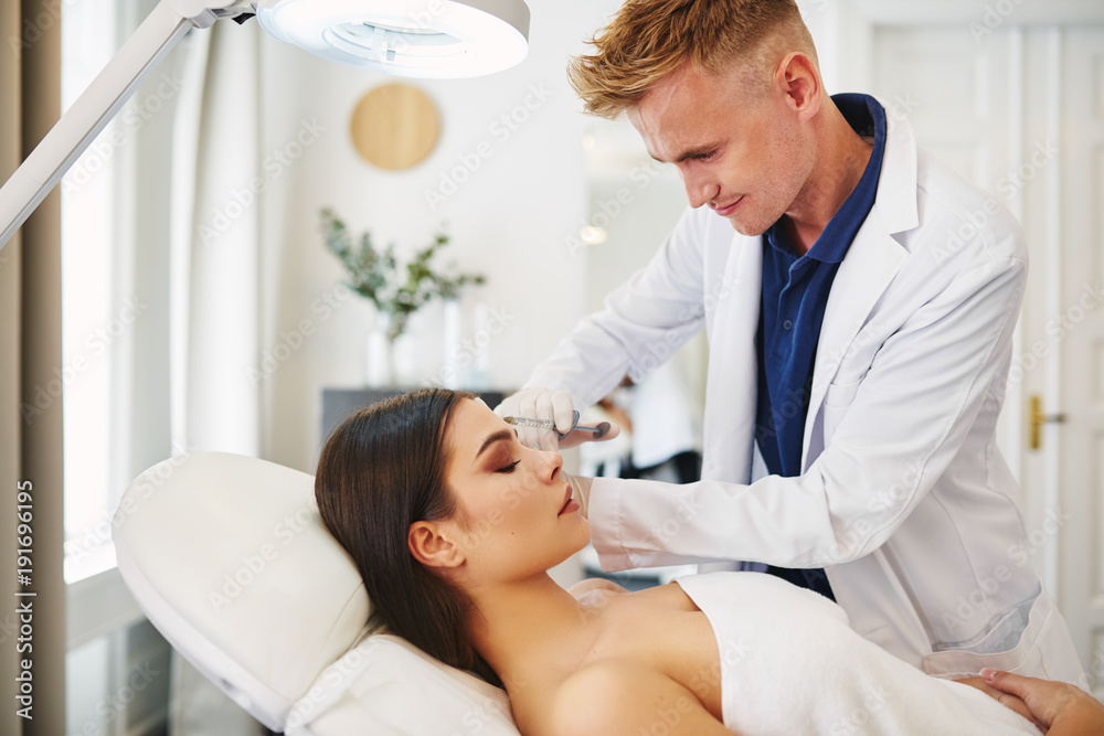 Doctor performing a botox injection on an attractive female client Doctor performing a botox injection on an attractive female client