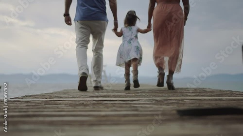4k Family skipping along a dock, looking at their backs,