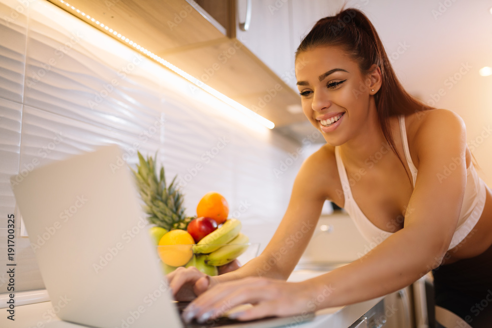 Sporty girl surfing the internet on kitchen table. Girl looking for recipe. Sporty girl surfing the internet on kitchen table. Girl looking for recipe.
