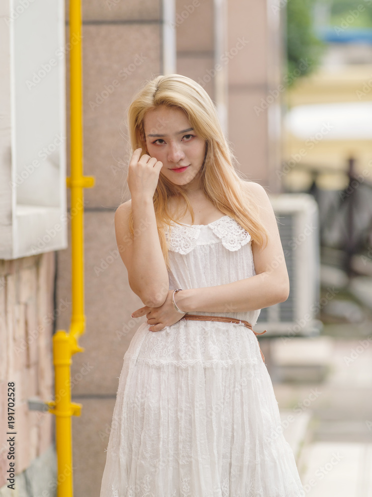 Beautiful Chinese young girl wearing a white dress in summer park. Outdoor fashion portrait of glamour young Chinese cheerful stylish lady. Emotions, people, beauty and lifestyle concept.