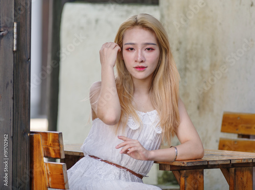 Beautiful Chinese young girl wearing a white dress in summer park. Outdoor fashion portrait of glamour young Chinese cheerful stylish lady. Emotions, people, beauty and lifestyle concept.