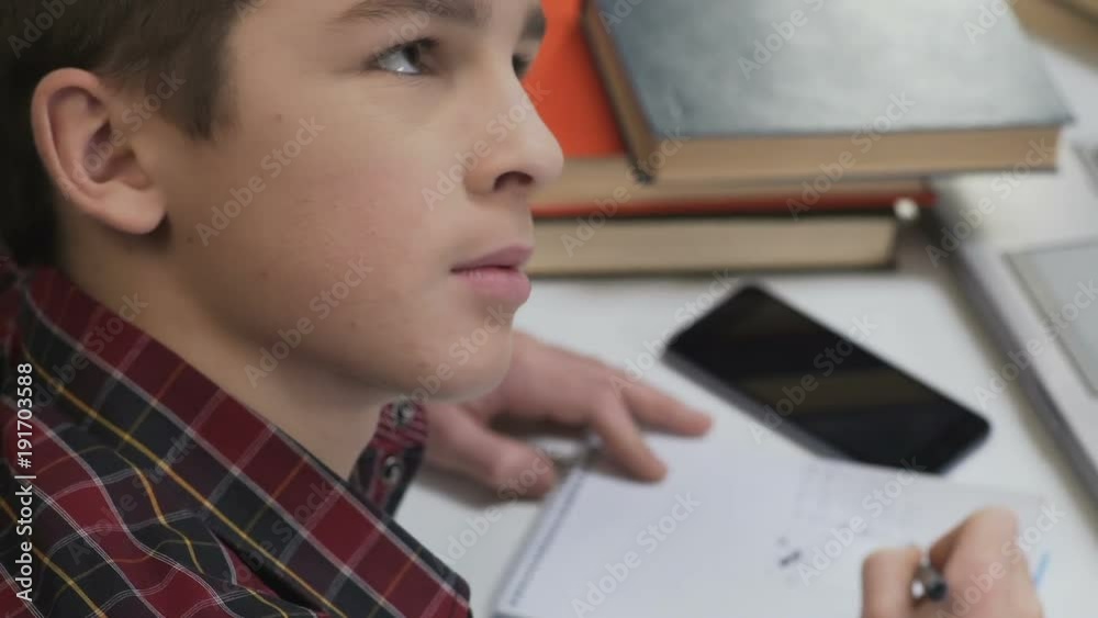 Boy sighs while doing homework, parents control education process, point of view