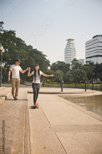 Young people use skatboard for relaxing time together outdoor at the city in the park