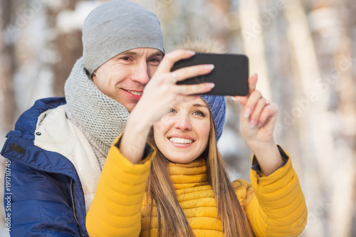 Portrait of young couple in a bright clothes do a selfie in a forest in the winter © kristinakibler