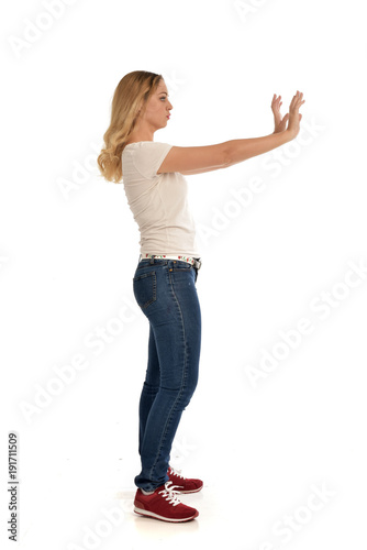 full length portrait of blonde girl wearing simple shirt and jeans, standing pose on white background.