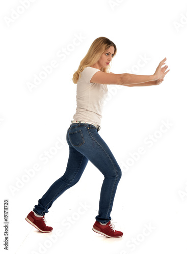 full length portrait of blonde girl wearing simple shirt and jeans, standing pose on white background.