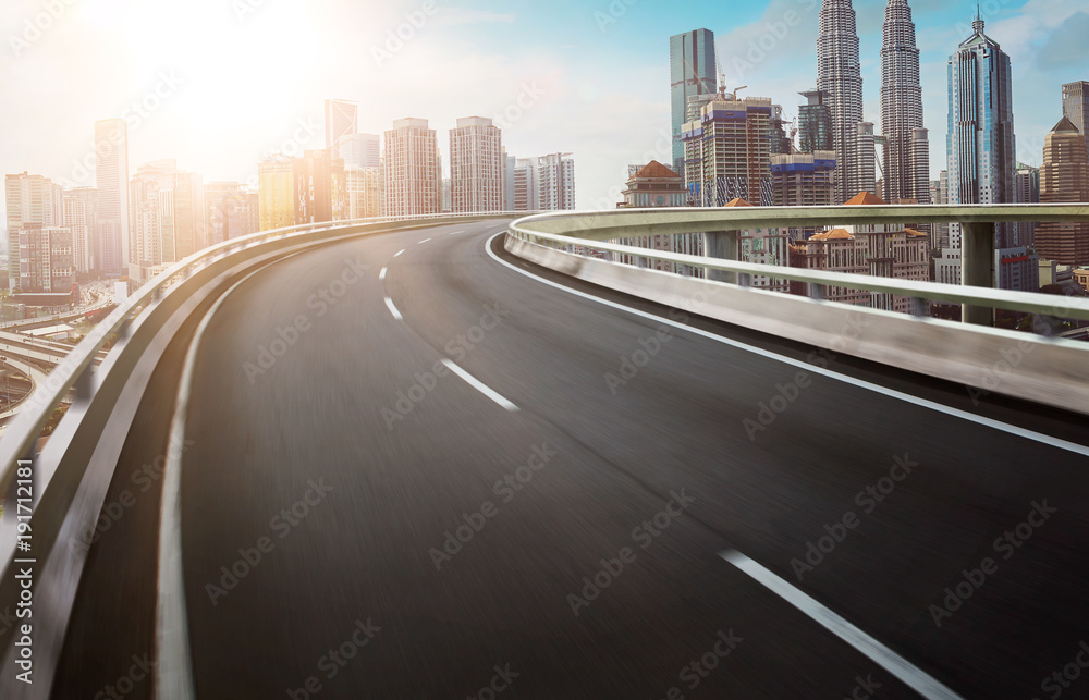 Motion curvy flyover asphalt highway road with modern cityscape skyline view . Sunrise scene . Motion curvy flyover asphalt highway road with modern cityscape skyline view . Sunrise scene .