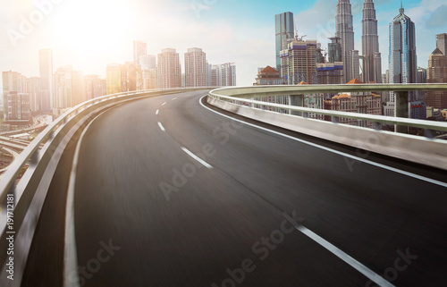 Motion curvy flyover asphalt highway road with modern cityscape skyline view  . Sunrise scene .