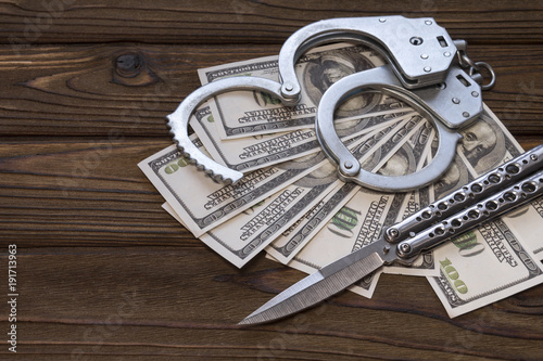 handcuffed knife and money dollars. Crime and punishment, criminal, theft. Armed attack.