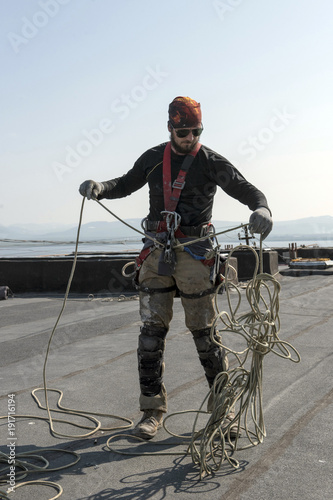 Obraz na płótnie steeplejack testing his gear on the roof of the building