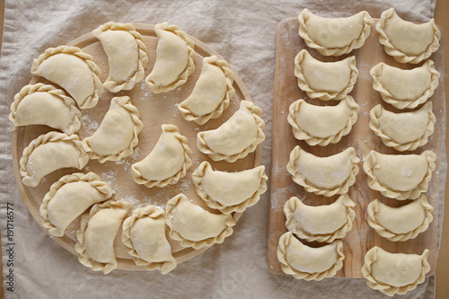 Dumplings raw on a wooden round board on a linen beige napkin. Traditional homemade food. traditional dish of Russian and Ukrainian cuisine