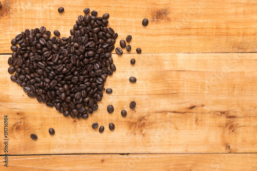 Coffee bean in shape of hearts on wooden of brown background, copy space for presentation product