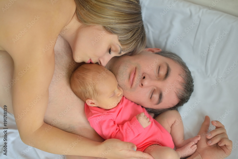 The newborn girl fell asleep with her mother and father The newborn girl fell asleep with her mother and father