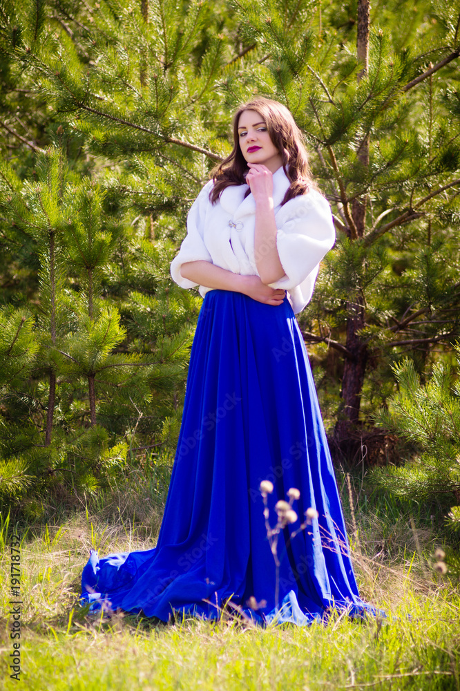 Beautiful fashion model in a dress in a green park in the summer . Blue dress. Beautiful fashion model in a dress in a green park in the summer . Blue dress.