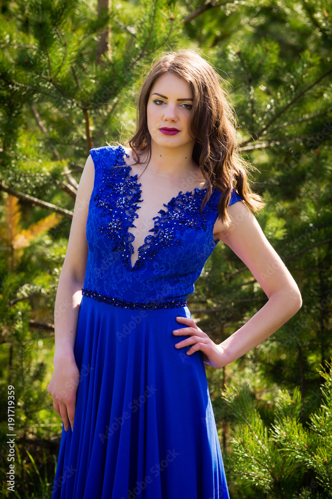Beautiful fashion model in a dress in a green park in the summer . Blue dress. Beautiful fashion model in a dress in a green park in the summer . Blue dress.