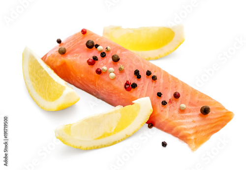 Fillet of red fish with slices of lemon and spices on white background.