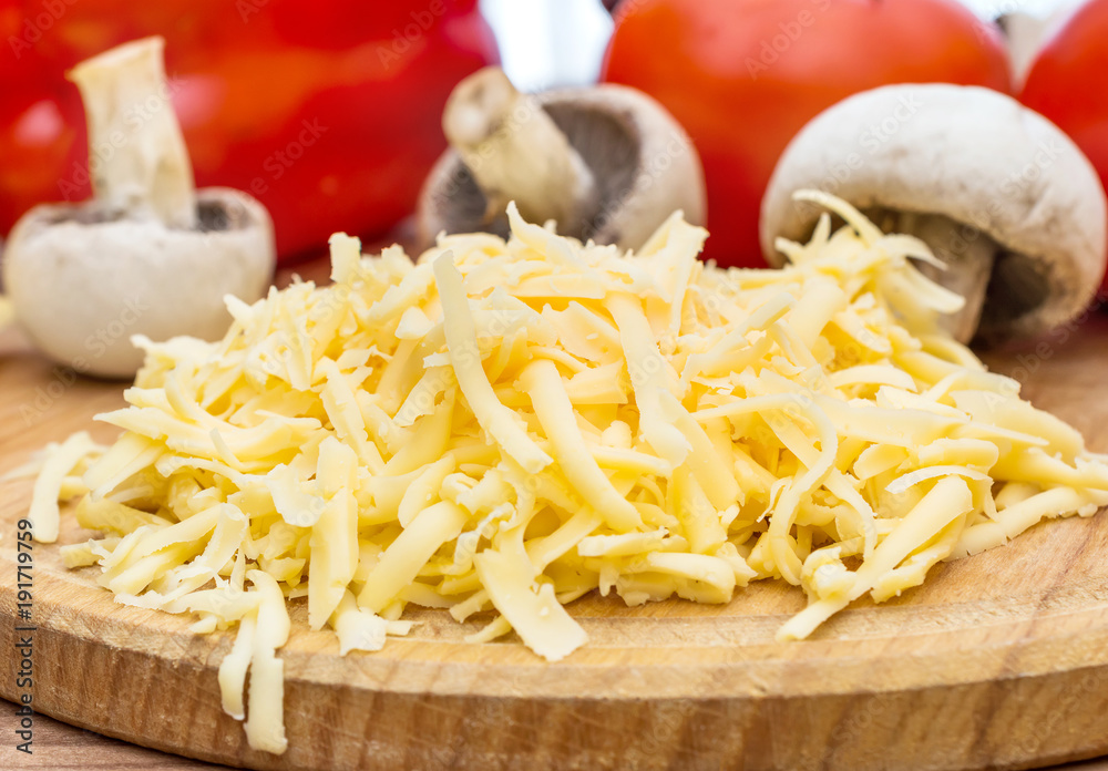 Grated cheese with vegetables on the cutting board. Close up.