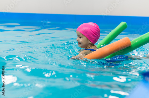 A little girl of European appearance floating in the pool on inflatable toy