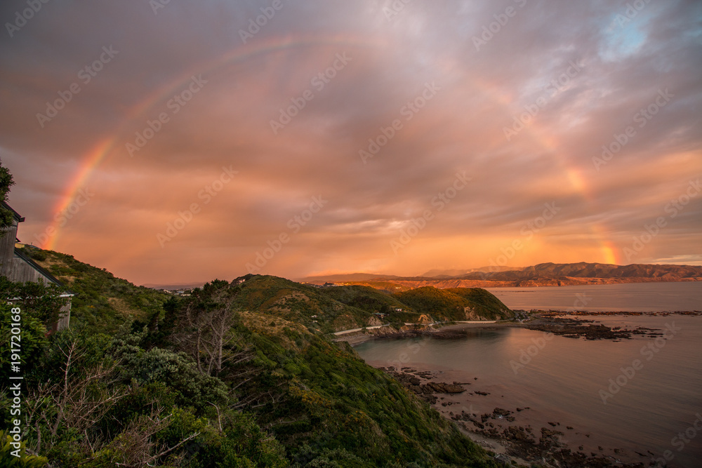 Rainbow and sunset along ocean coastline