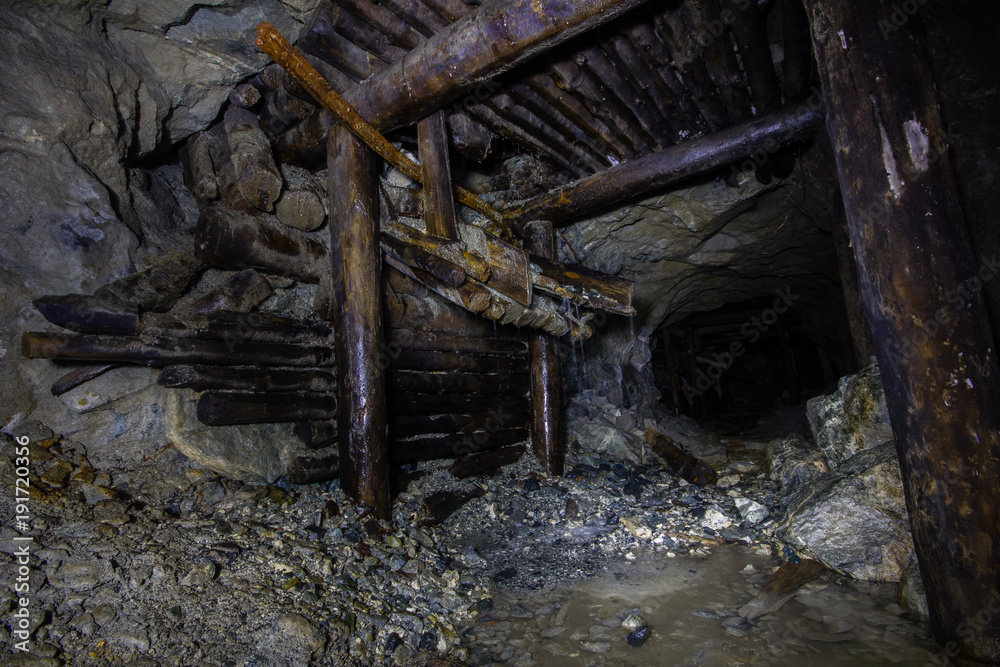 Underground abandoned gold ore mine shaft tunnel gallery with wooden timbering