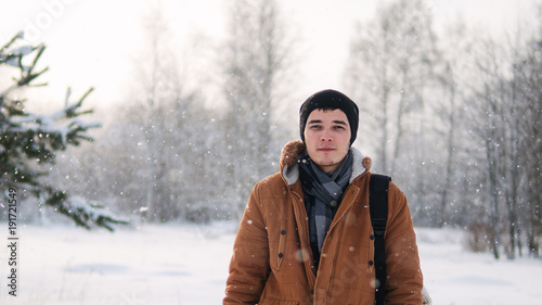 portrait of young man in brown jacket in winter forest