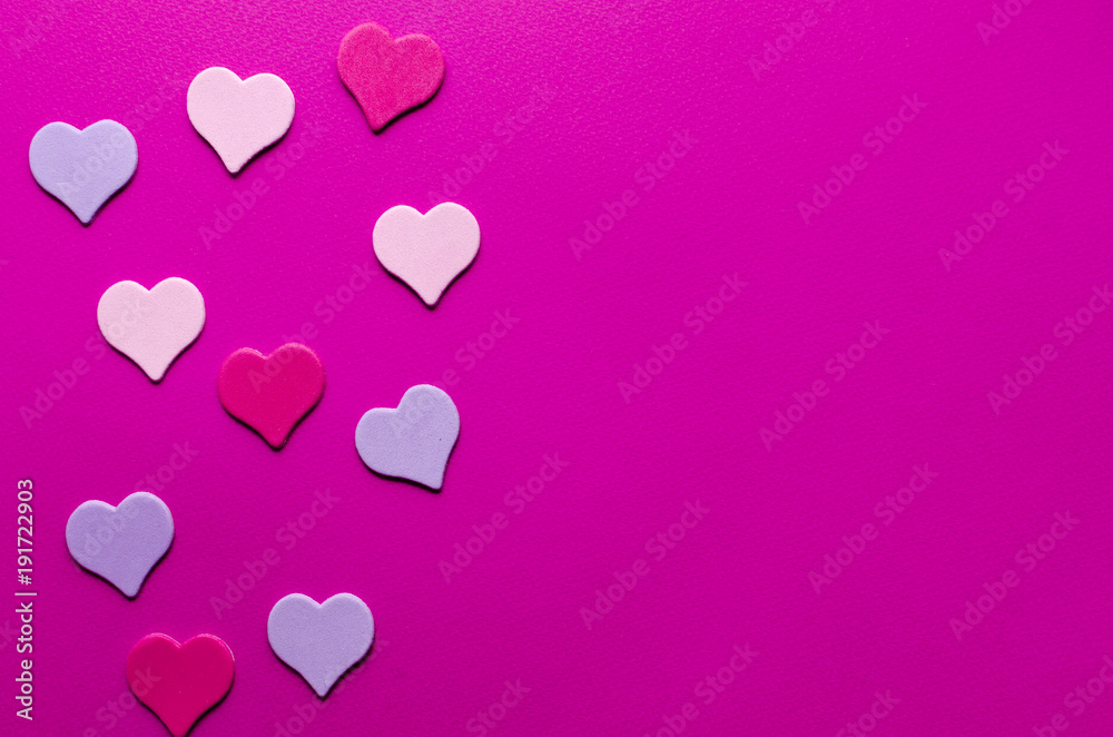colored paper hearts on pink paper background