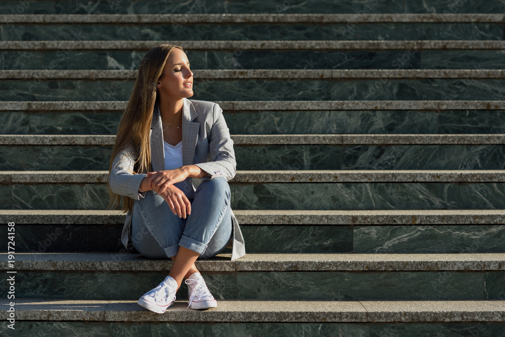 Beautiful young caucasian woman with eyes closed sitting on steps