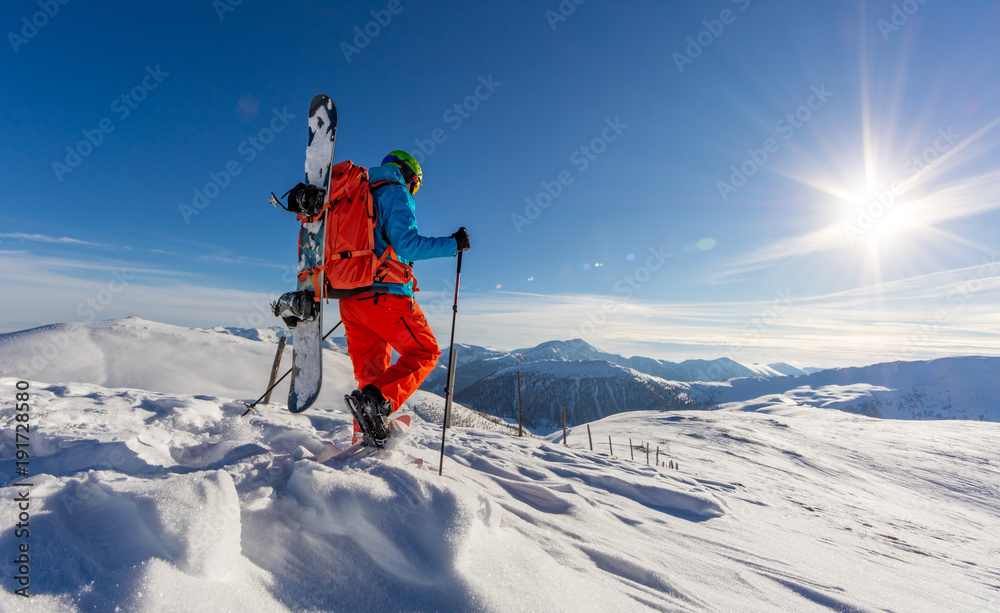 Snowboarder walking on snowshoes in powder snow.