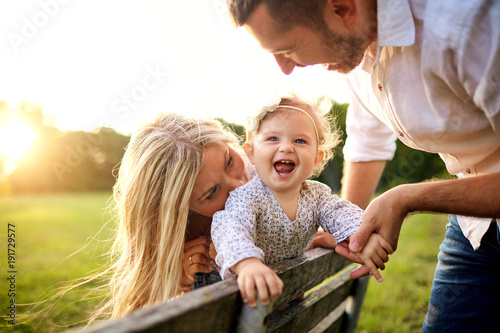 Happy family in a park in summer autumn. Mother, father and baby play in nature in the rays of sunset. photo