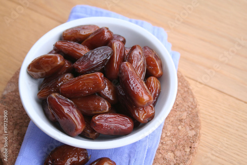 Bowl of dried dates on wooden background
