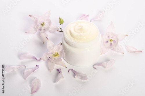 Cute flowers and petal and a jar of natural body cream isolated on white background