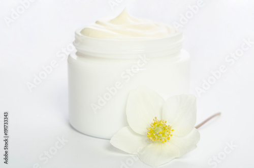 Cute flower and a jar of natural body cream isolated on white background