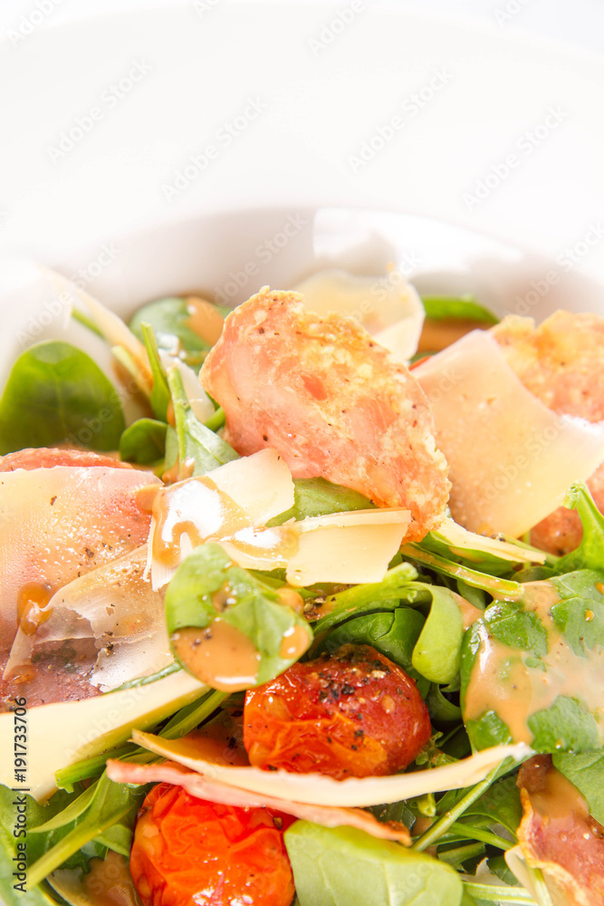 Baby spinach, dry sausage, matured cheese, roast tomatoes, thyme-balsamic vinaigrette salad on a white background Baby spinach, dry sausage, matured cheese, roast tomatoes, thyme-balsamic vinaigrette salad on a white background