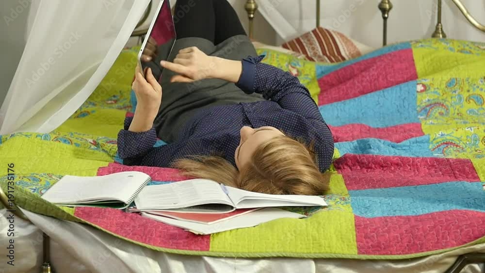 Friendly female student reading on digital tablet lying in bed. beautiful woman on-line education in home. slow motion