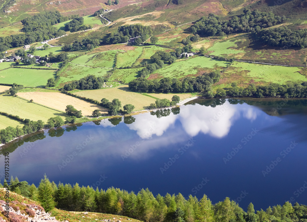 Reflections of white clouds in a blue sky on Lake Buttermere in the English Lake District, UK.