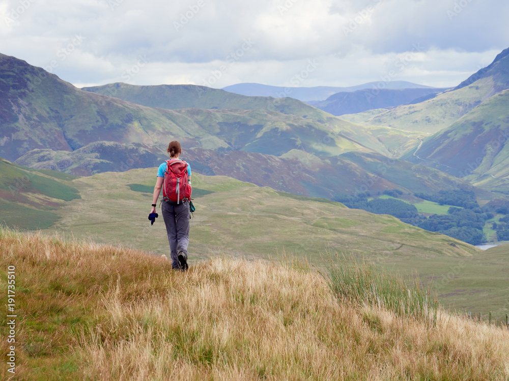 A female hiker walking off the summit of Great Borne towards Loweswater Fell in the English Lake District, UK.